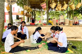 Các em học sinh trải nghiệm đan gùi với nghệ nhân làng Ngơm Thung, xã Ia Pết, huyện Đak Đoa. Ảnh: L.N
