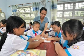 Cô Nguyễn Thị Thúy Nga-Giáo viên Trường Tiểu học Phan Chu Trinh hướng dẫn các em học bài. Ảnh: V.C