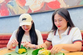 Chị Lê Thị Ni Na (bìa phải) gói xôi cốm cho khách hàng. Ảnh: M.K