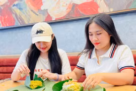 Chị Lê Thị Ni Na (bìa phải) gói xôi cốm cho khách hàng. Ảnh: M.K