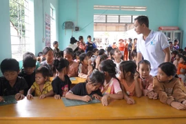 Thầy Lê Văn Bình hướng dẫn em đã biết chữ học tiếng Anh tại lớp học tình thương ở làng Khôi. 