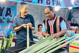 Ông Yaih (bên phải) chế biến món cơm lam truyền thống của người Jrai. Ảnh: Trần Dung