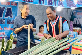 Ông Yaih (bên phải) chế biến món cơm lam truyền thống của người Jrai. Ảnh: Trần Dung