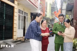 Tổ công nghệ số cộng đồng cùng cán bộ công an phường Phủ Lý, tỉnh Ninh Bình đến từng khu dân cư hướng dẫn người dân tham gia góp ý dự thảo các văn kiện Đại hội XIV của Đảng thông qua ứng dụng VNeID. Ảnh: Nguyễn Chinh/TTXVN
