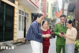 Tổ công nghệ số cộng đồng cùng cán bộ công an phường Phủ Lý, tỉnh Ninh Bình đến từng khu dân cư hướng dẫn người dân tham gia góp ý dự thảo các văn kiện Đại hội XIV của Đảng thông qua ứng dụng VNeID. Ảnh: Nguyễn Chinh/TTXVN