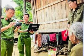 Cán bộ Công an xã Kbang chụp ảnh Căn cước cho cụ Đinh Qiu (ở làng Nak) ngay tại bậc thềm nhà sàn.