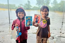 Các em nhỏ mỉm cười hạnh phúc khi nhận những bức hình đầu tiên của mình. Ảnh: Ngọc Duy