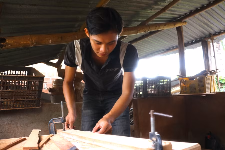 Anh Trần Nhất Hùng (tổ 1, phường Ngô Mây, thị xã An Khê) tỉ mẩn xẻ từng thanh gỗ để làm lồng chim. Ảnh: Ngọc Minh