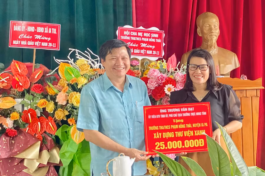Phó Chủ tịch Thường trực HĐND tỉnh Trương Văn Đạt trao 25 triệu đồng cho Hiệu trưởng Trường Tiểu học và THCS Phạm Hồng Thái để hoàn thiện "Thư viện xanh". Ảnh: Mai Linh