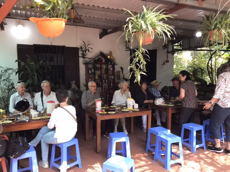 Du khách tàu biển quốc tế chờ được phục vụ khoai lang luộc và nước chè tươi tại một nhà dân ở huyện Vân Đồn trưa 20-2. Ảnh: Nguyễn Hùng