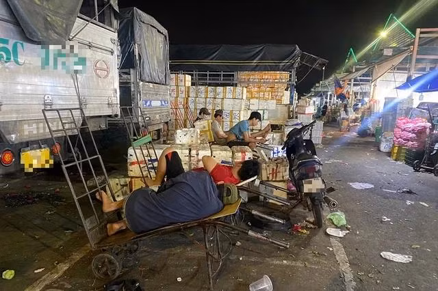 Những người làm bốc xếp ở chợ đầu mối Thủ Đức tranh thủ nghỉ ngơi trên xe kéo hàng chờ chuyến xe tiếp theo