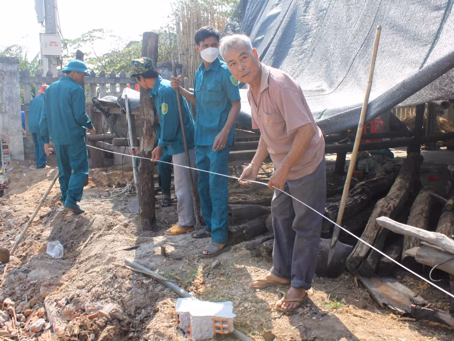 Ông Phùng Văn Sau (bìa phải) cùng lực lượng dân quân thị trấn căng dây làm lại hàng rào sau khi hiến đất làm đường. Ảnh: Vũ Chi Ông Phùng Văn Sau (bìa phải) cùng lực lượng dân quân thị trấn căng dây làm lại hàng rào sau khi hiến đất làm đường. Ảnh: Vũ Chi
