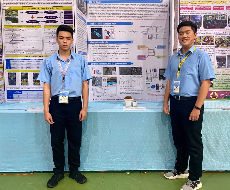 Em Văn Gia Hy (bìa phải) và em Đỗ Hà Minh Thái bên poster giới thiệu dự án của mình tại Cuộc thi khoa học kỹ thuật cấp tỉnh học sinh trung học năm học 2022-2023. Ảnh: Mộc Trà