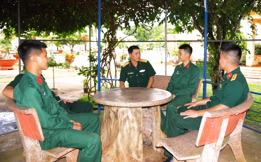 Trung tá Nguyễn Thanh Tú (ngồi giữa) trò chuyện nắm tâm tư, nguyện vọng của các cán bộ, chiến sĩ. Ảnh: V.H