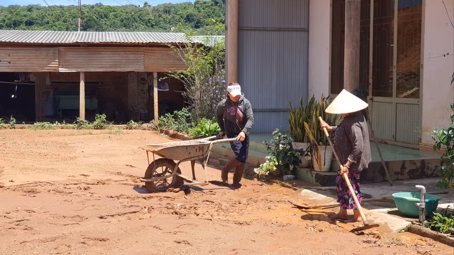 Gia đình bà Phạm Thị Cà (thôn Thanh Bình) dọn dẹp bùn đất tràn vào nhà sau cơn mưa lớn. Ảnh: Hà Phương