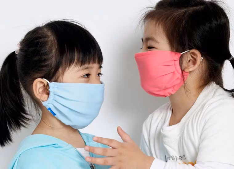 Để phòng tránh bệnh viêm màng não, cha mẹ nên cho trẻ mang khẩu trang khi đi ra ngoài. Ảnh minh họa Vinmec