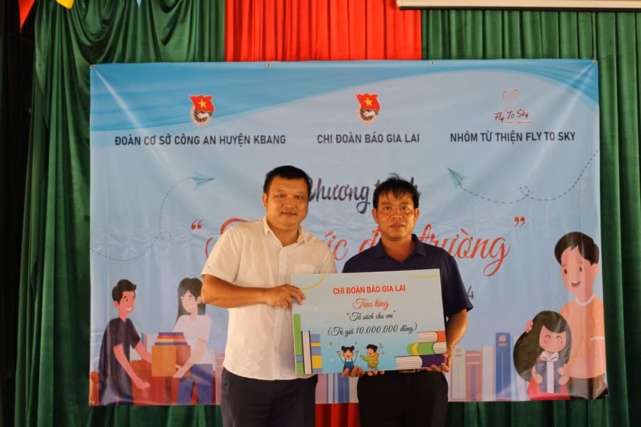 Ông Lê Tiến Dũng-Phó Trưởng phòng Thư ký tòa soạn Báo Gia Lai (bìa trái) trao tặng "Tủ sách cho em". Ảnh: Hoàng Hoài