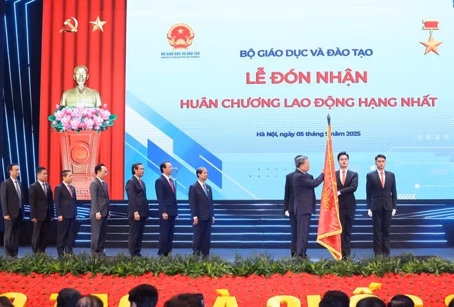 Tổng Bí thư Tô Lâm gắn Huân chương Lao động hạng Nhất lên lá cờ truyền thống của Bộ Giáo dục-Đào tạo. (Ảnh: Thống Nhất/TTXVN)