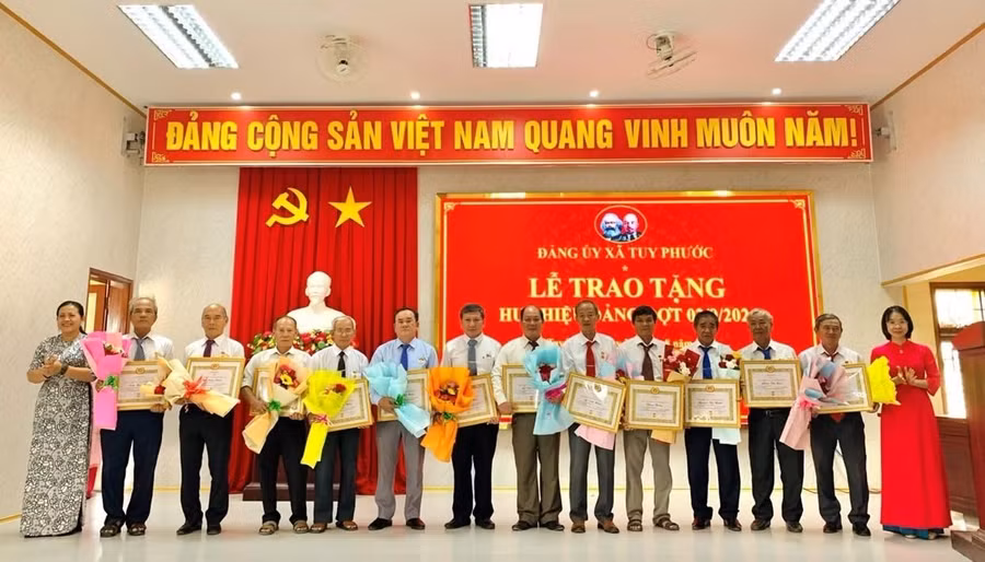 Lãnh đạo Đảng ủy xã Tuy Phước trao huy hiệu Đảng cho các đảng viên. Ảnh: Thùy Duyên