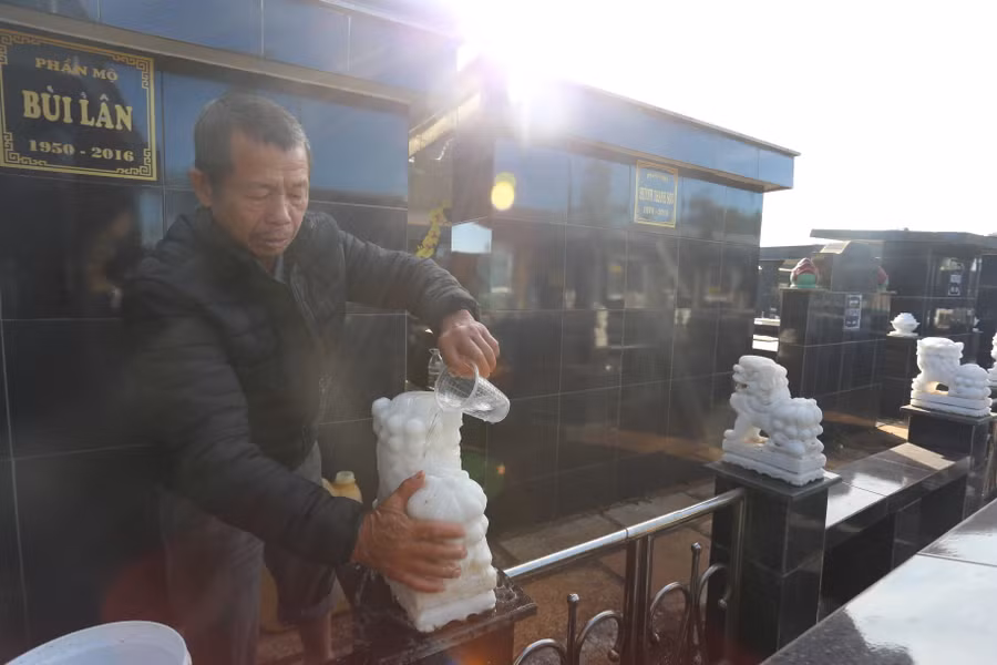 Ông Lê Lộc đang lau chùi phần mộ của anh trai. Ảnh: Văn Ngọc