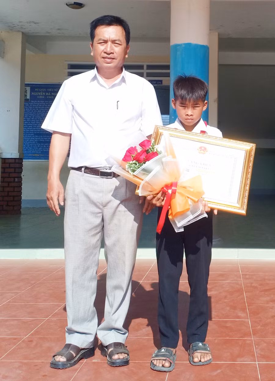 Thừa ủy quyền của Chủ tịch UBND tỉnh, ông Ksor Suy-Phó Chủ tịch UBND huyện tặng bằng khen cho em Kpă Nguyên. Ảnh: Như Loan