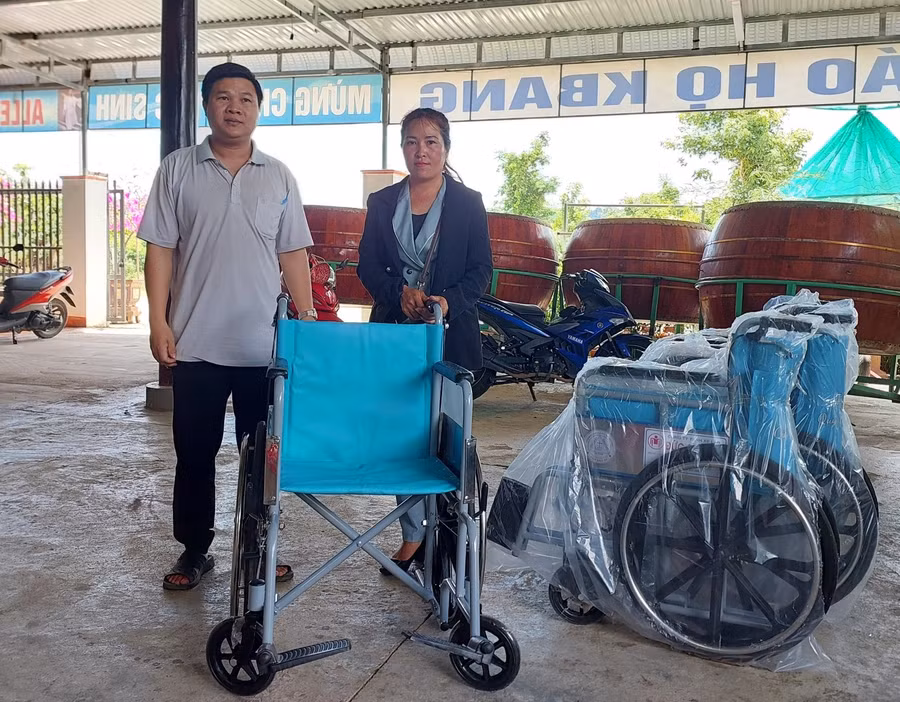 Đại diện đoàn công tác trao xe lăn cho gia đình người khuyết tật. Ảnh: Hồng Ngọc