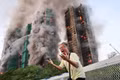 Một người đàn ông cầu xin giúp đỡ trong lúc ngọn lửa bao trùm cụm chung cư Wang Fuk Court. Ảnh: Reuters
