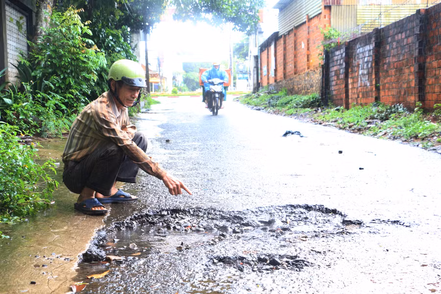Ông Hoàng Xuân Huy chỉ cho P.V những chỗ hư hỏng năng trên đường An Dương Vương. Ảnh: Quang Tấn