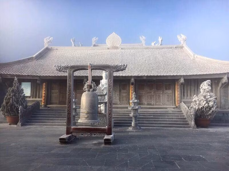 Gác chuông và ngôi chùa trên đỉnh núi bị phủ một màu trắng xóa