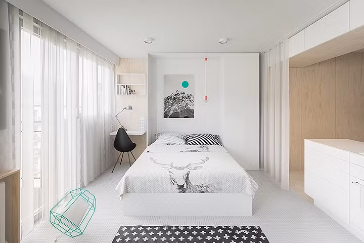 Chiếc giường thông tin được hạ xuống từ tủ tường. Dây đèn màu sắc bắt mắt tạo ra một sự tương phản nổi bật với các nội thất trong phòng.