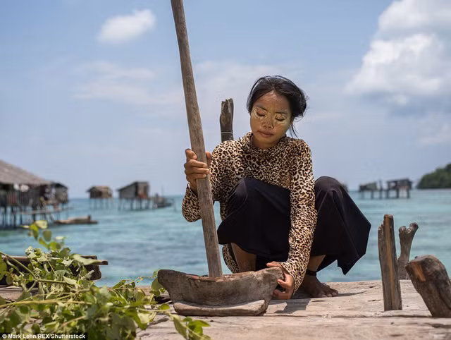  Một cô gái giã bột để bôi lên mặt. Đây là thứ bột tự chế giúp chống lại thứ nắng gay gắt trên biển