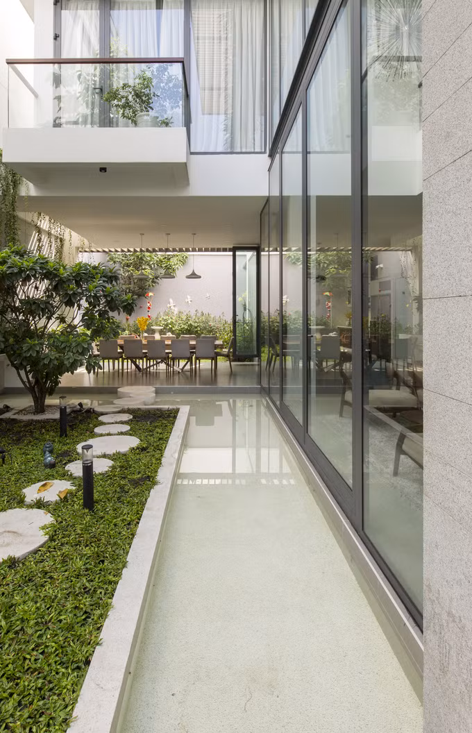 Để các không gian chức năng đều có view nhìn ra sân vườn, các kiến trúc sư đã thiết kế những bức tường kính cường lực. Tường kính giúp xóa nhòa ranh giới giữa bên trong và ngoài nhà, mang không gian sân vườn vào trong nhà và ngược lại.