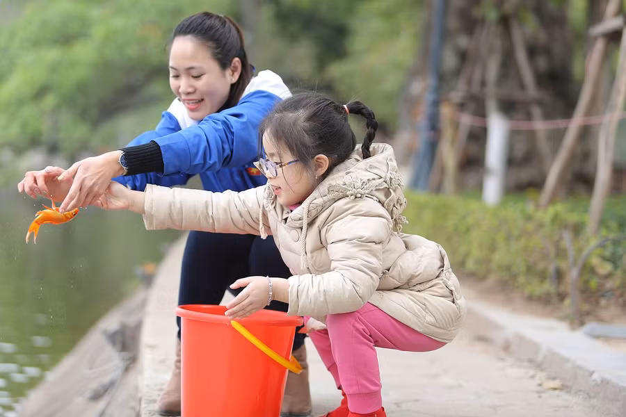 Bé gái thả cá chép trong ngày 23 tháng Chạp. Ảnh: VietNamNet.