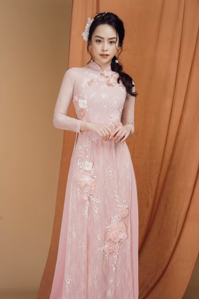  Áo dài màu hồng pastel được điểm họa tiết hoa 3D theo hình chữ S tạo cảm giác về một thân hình mảnh dẻ, tôn lên sự nữ tính của người con gái.