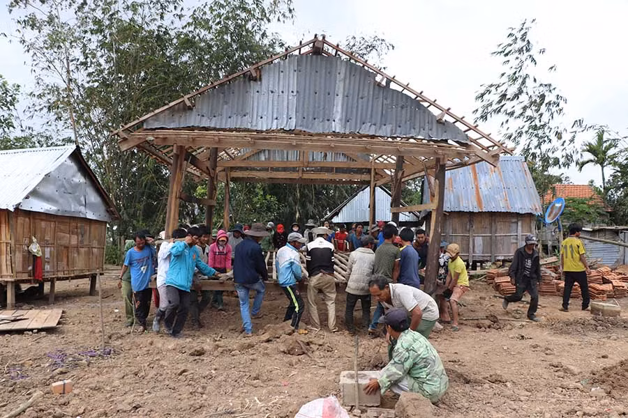  Người dân làng Pơ Nang chung sức di dời nhà. Ảnh: N.M