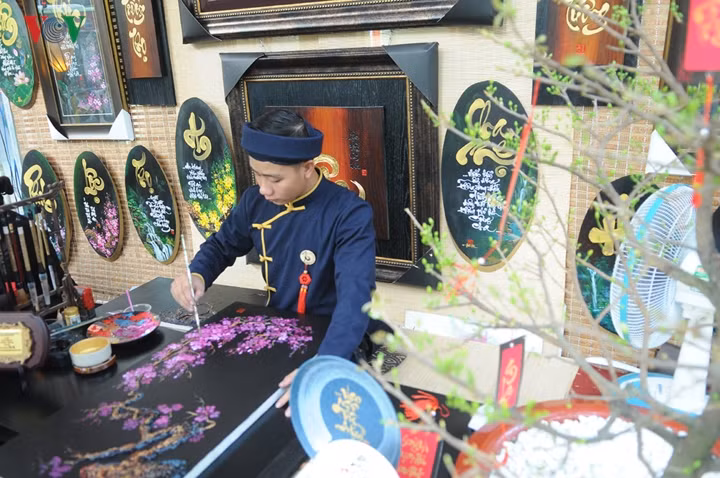Ông Đồ trẻ say sưa vẽ tranh bán cho khách.