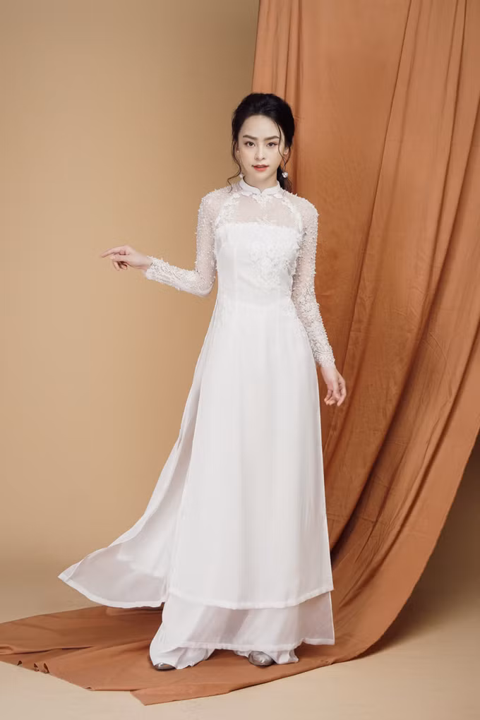 Tà áo vẫn giữ phom dáng truyền thống với cổ cao 2 cm nhưng đã được biến tấu đôi nét, áp dụng xu hướng cổ 2 trong 1 phổ biến trong thời trang cưới và được kết nối bởi lớp voan mỏng.