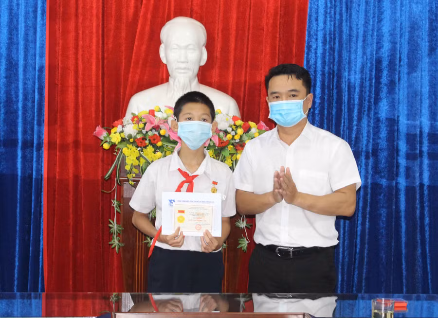 Anh Đỗ Duy Nam (bìa phải)-Phó Bí thư Tỉnh Đoàn trao tặng huy hiệu “Tuổi trẻ dũng cảm” cho em Trần Nguyễn Anh Duy. Ảnh Phan Lài.