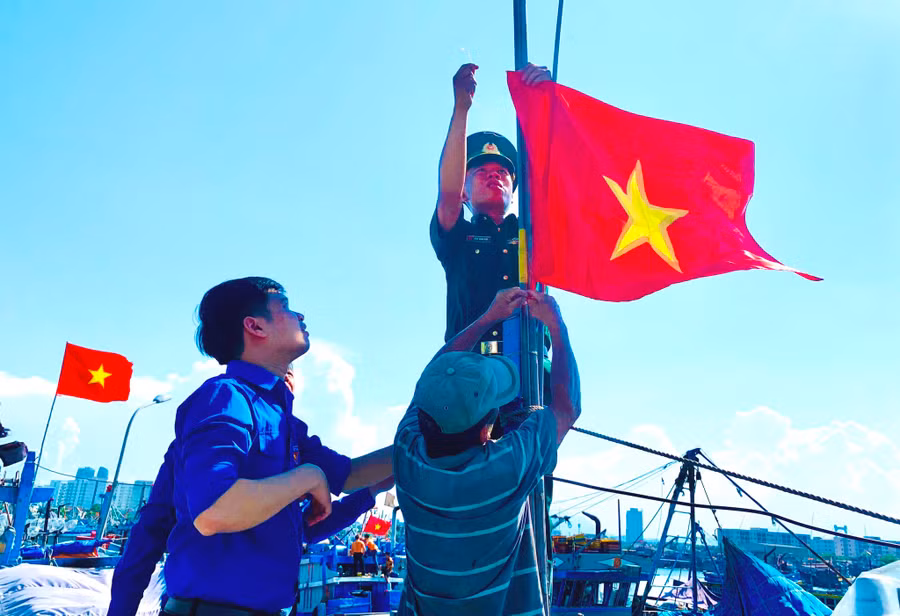 Trung úy Phan Hoàng Hiệp treo cờ Tổ quốc lên tàu cá chuẩn bị vươn khơi, bám ngư trường Hoàng Sa - ẢNH: S.X