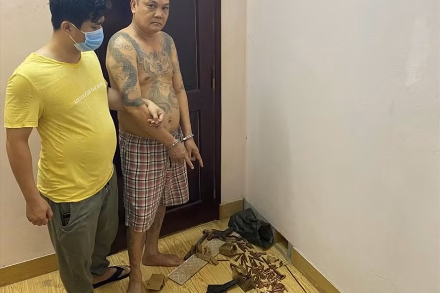 Đối tượng Cao Tiến Dũng cùng số vũ khí quân dụng được Công an tỉnh Quảng Ninh tìm thấy tại nhà riêng ở thành phố Cẩm Phả. Ảnh: CAQN