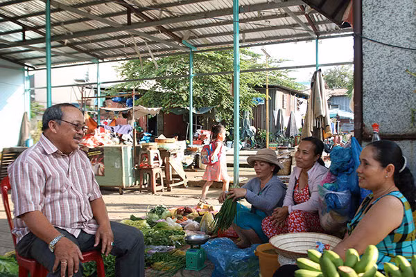 Ông Năm Hấp trò chuyện cùng những người buôn bán trong khu chợ mang tên ông trên đường T1 (quận Tân Phú, TP. HCM).