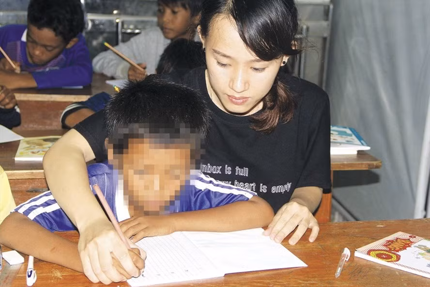 Các em nhỏ được cô giáo kèm cặp, tập viết những nét chữ đầu tiên.