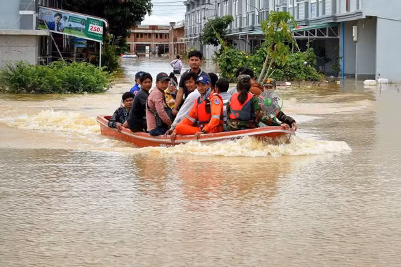 Một nhóm cứu hộ đang sơ tán người dân bằng xuồng máy vượt qua vùng nước ngập ở ngoại ô thủ đô Phnom Penh ngày 18-10.