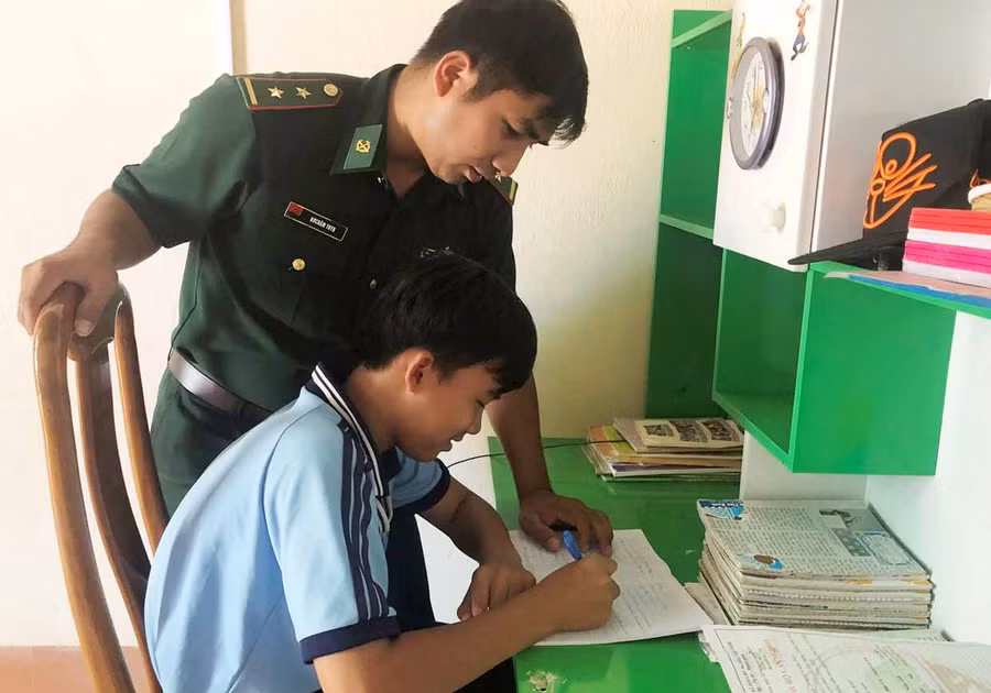 Trung úy Rơ Châm Tuyn hướng dẫn cháu Nguyễn Quốc Tĩnh học bài. Ảnh: Phương Dung Trung úy Rơ Châm Tuyn hướng dẫn em Nguyễn Quốc Tĩnh học bài. Ảnh: Phương Dung