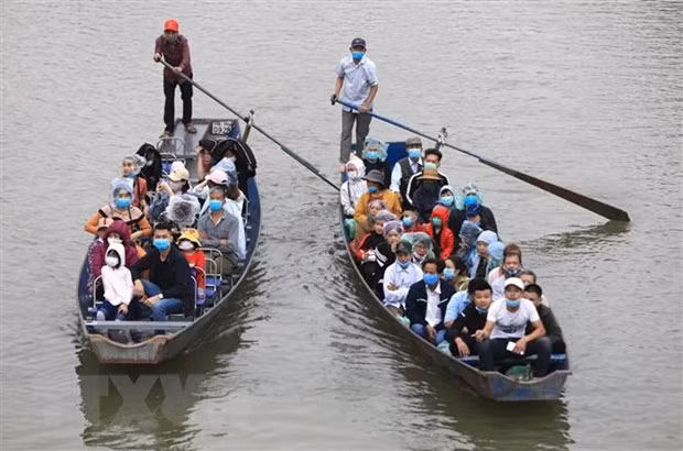 Du khách đi đò vào chùa Hương đều phải đeo khẩu trang phòng chống dịch. (Ảnh: Thành Đạt/TTXVN)