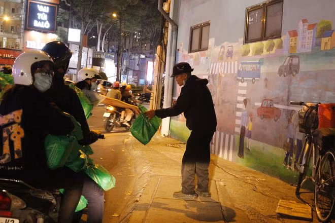 Các thành viên Đội kết nối tình nguyện tặng suất ăn nghĩa tình cho người vô gia cư trên đường phố