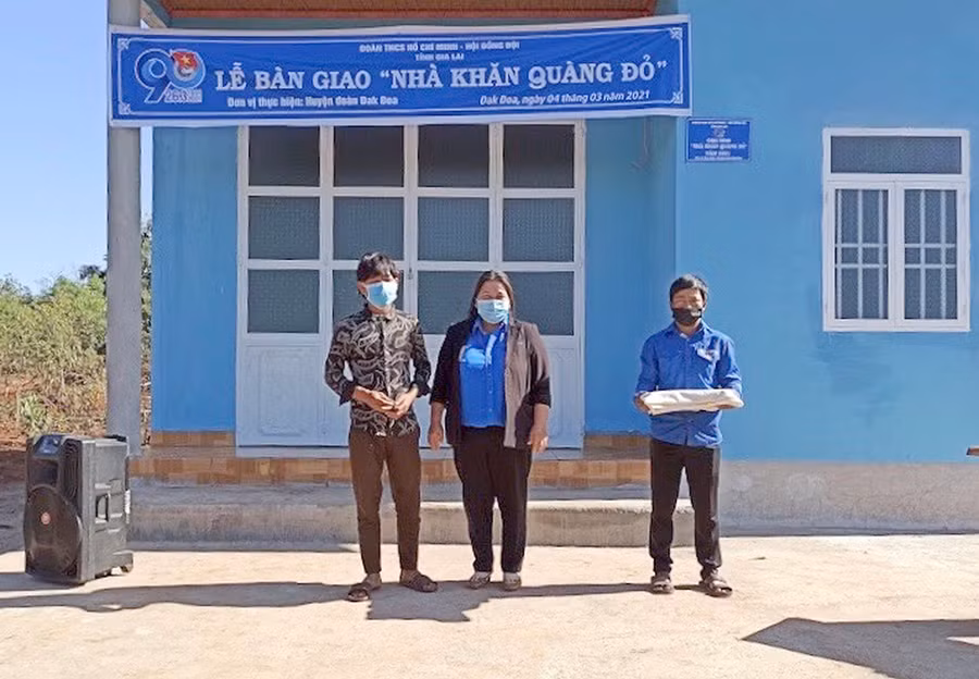 Chị Hà Thị Giang Thảo-Bí thư Tỉnh Đoàn trao nhà Khăn quàng đỏ cho em Kup (bìa trái; học sinh Trường THCS Anh Hùng Wừu, xã Đak Sơ Mei, huyện Đak Đoa). Ảnh: Phan Lài
