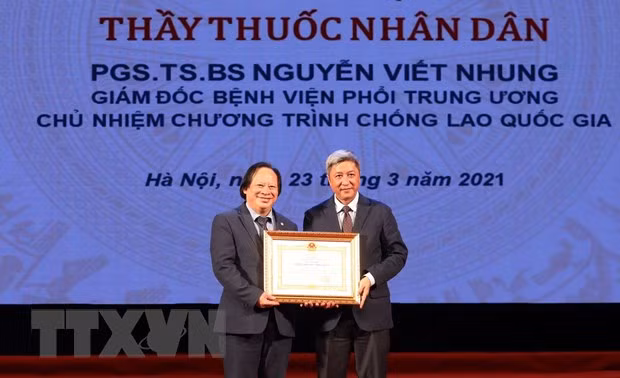 Thứ trưởng Bộ Y tế Nguyễn Trương Sơn trao danh hiệu Thầy thuốc Nhân dân cho phó giáo sư Nguyễn Viết Nhung. (Ảnh: Anh Tuấn/TTXVN)