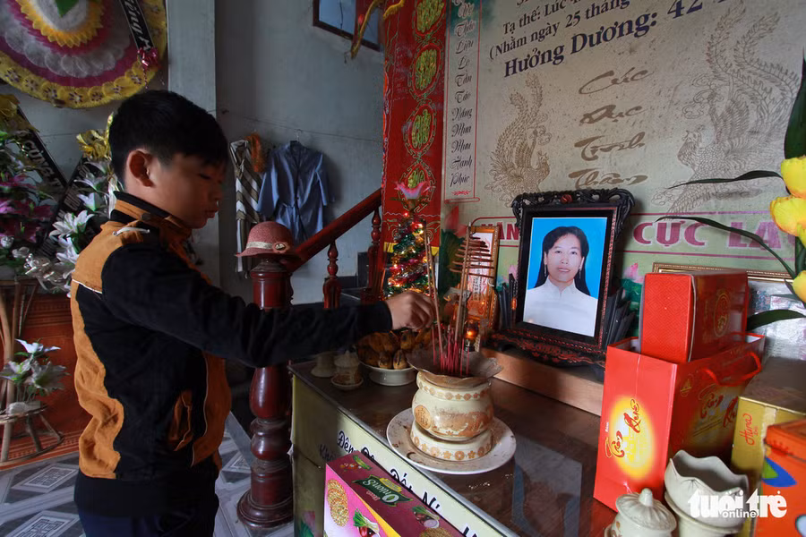 Con trai chị Lương Thị Thu Dung thắp nhang bên di ảnh mẹ.