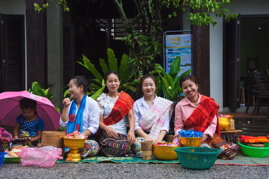  Các cô gái Lào dậy từ rất sớm để chuẩn bị cho lễ cúng dường, nở nụ cười thật tươi với du khách ghé qua